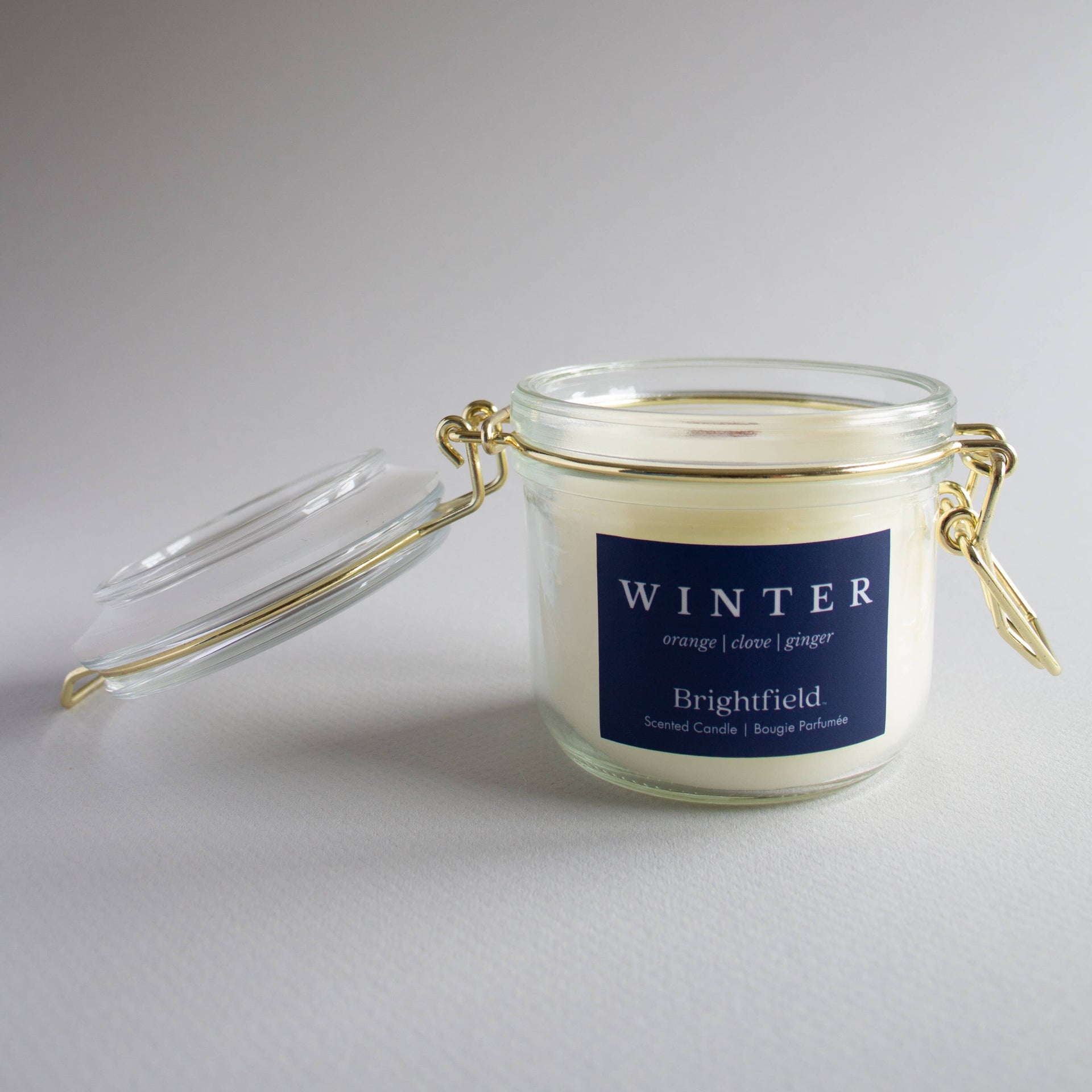 Glass candle jar with a blue label on a gray background