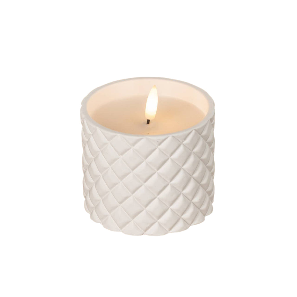 White textured candle with a lit flame on a wooden surface