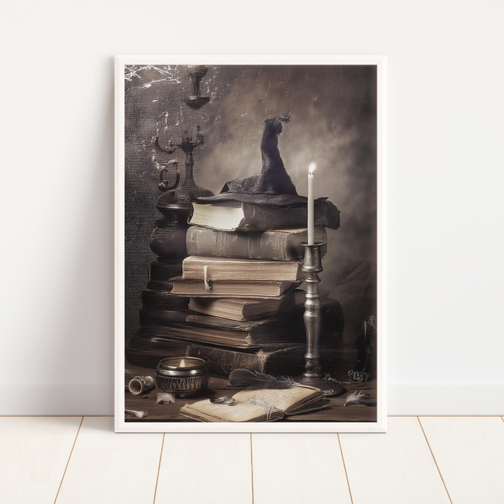 Framed artwork of a still life scene with books, candle, and other objects on a white wall.