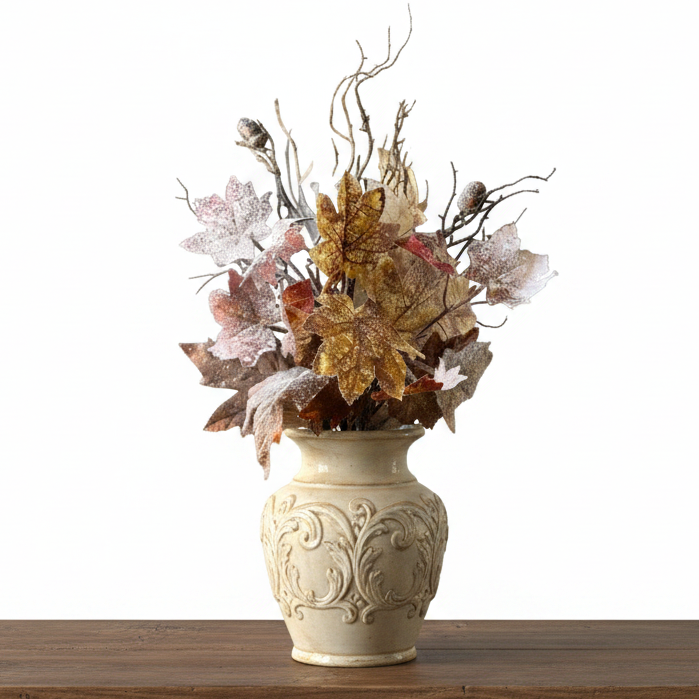 Autumn leaf floral arrangement in a dark metal vase, featuring flocked maple leaves in gold, brown, and pinkish tones, displayed on a rustic wooden surface.